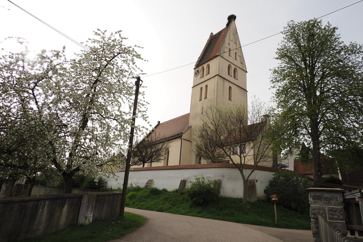 Kirche Haselbach umgeben von blühenden Bäumen und einer ländlichen Umgebung.